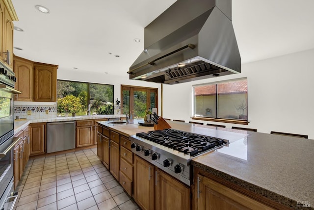 kitchen with light tile patterned floors, stainless steel appliances, backsplash, a sink, and exhaust hood