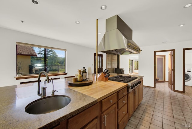 kitchen with recessed lighting, a sink, island exhaust hood, washer / dryer, and stainless steel gas stovetop