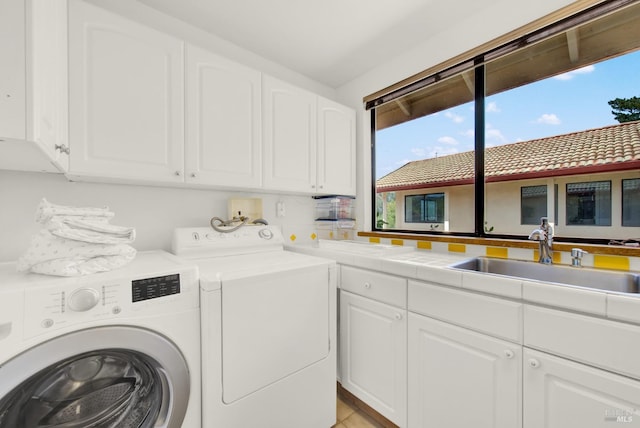clothes washing area featuring light tile patterned floors, washing machine and clothes dryer, a sink, and cabinet space