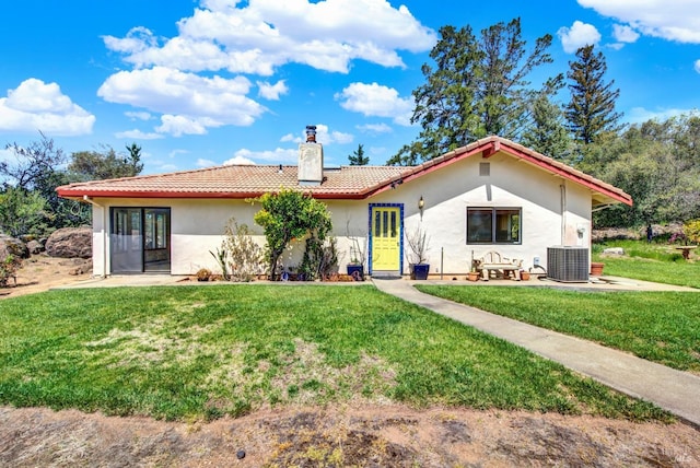 back of house featuring a yard, a chimney, and stucco siding