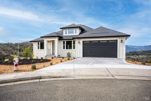 view of front of property featuring a mountain view, a garage, a shingled roof, driveway, and board and batten siding