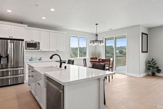 kitchen featuring appliances with stainless steel finishes, white cabinetry, a sink, and light stone counters