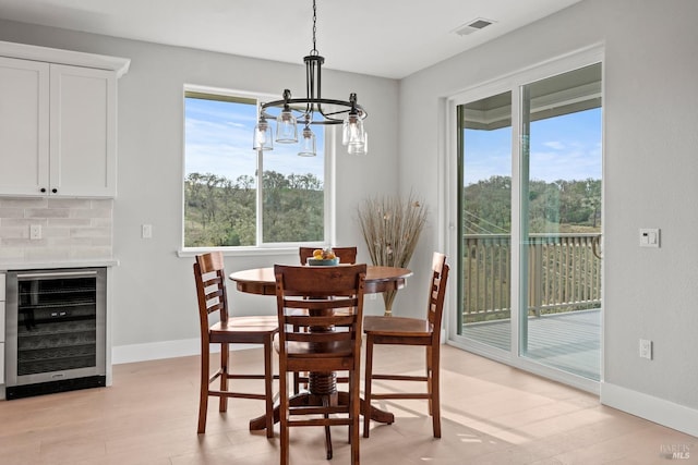 dining space featuring beverage cooler, visible vents, plenty of natural light, and light wood finished floors