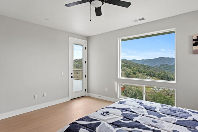 bedroom with visible vents, baseboards, a ceiling fan, light wood-style floors, and a mountain view