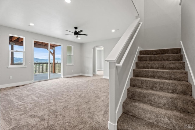 stairs featuring arched walkways, carpet floors, a mountain view, and baseboards