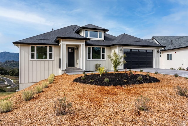 prairie-style home with an attached garage, a shingled roof, board and batten siding, and concrete driveway