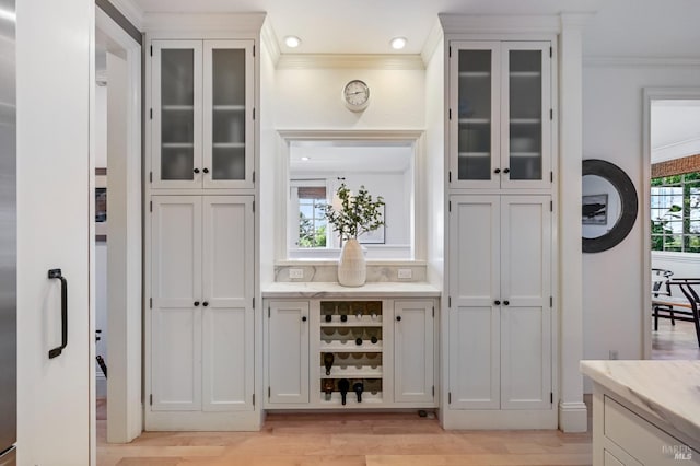 bar featuring plenty of natural light, light wood-style flooring, and crown molding