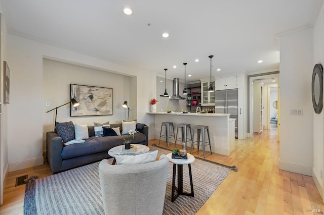 living room with recessed lighting, visible vents, light wood-style flooring, and baseboards