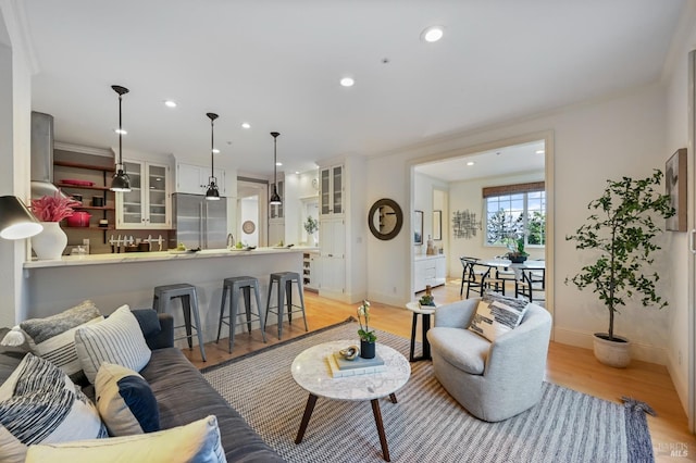 living room with recessed lighting, crown molding, light wood-style flooring, and baseboards