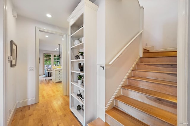 stairway with baseboards, wood finished floors, and recessed lighting