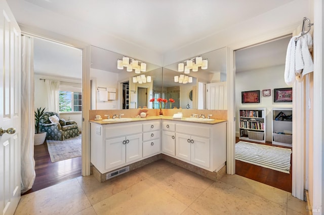 full bathroom featuring wood finished floors, visible vents, a sink, and double vanity