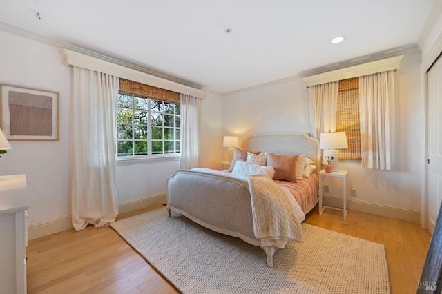 bedroom featuring baseboards, ornamental molding, and light wood-style floors