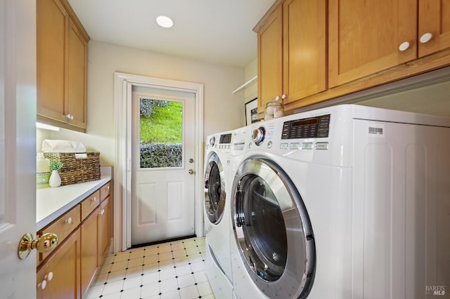 clothes washing area featuring light floors, separate washer and dryer, and cabinet space