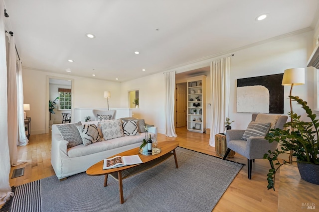 living area with recessed lighting, visible vents, crown molding, and light wood finished floors