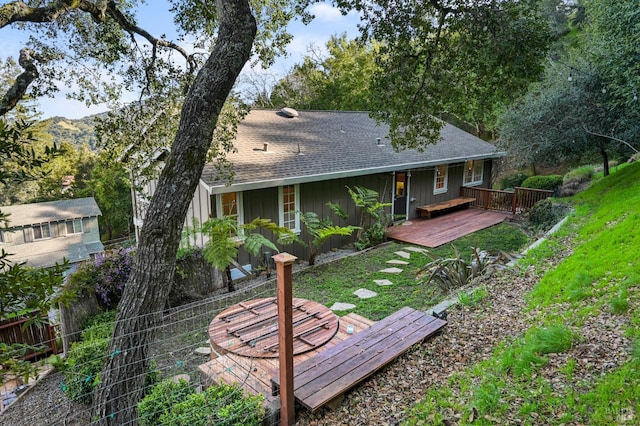 back of house featuring a yard, a shingled roof, board and batten siding, and a wooden deck