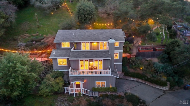 rear view of house with a shingled roof and driveway