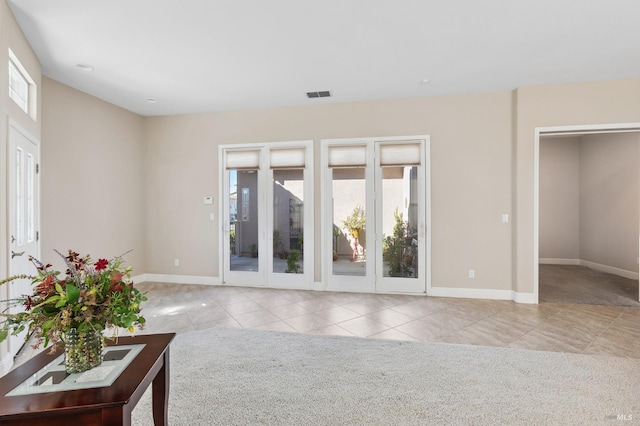 unfurnished living room featuring light carpet, light tile patterned floors, baseboards, and visible vents