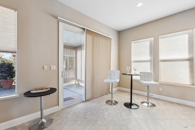 interior space featuring light tile patterned floors, baseboards, and a wealth of natural light