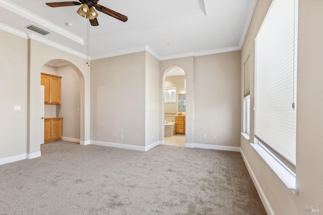 unfurnished room with arched walkways, a tray ceiling, light colored carpet, visible vents, and ornamental molding