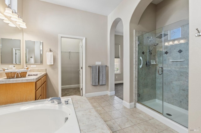 bathroom featuring a spacious closet, a shower stall, vanity, tile patterned flooring, and baseboards