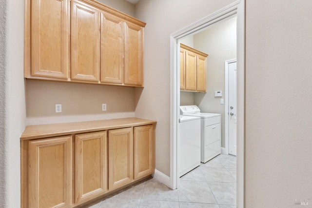 washroom featuring cabinet space, washer and clothes dryer, baseboards, and light tile patterned floors
