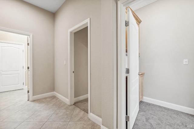 corridor featuring light tile patterned floors and baseboards