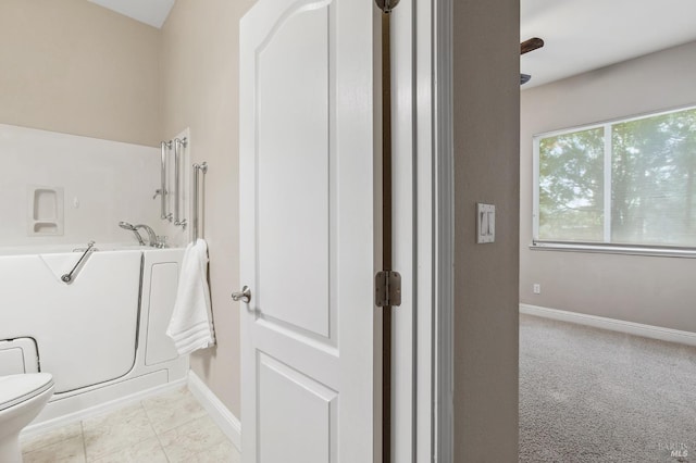 bathroom featuring tile patterned floors, toilet, baseboards, and a bath