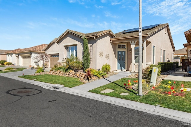 view of front facade featuring solar panels, an attached garage, and stucco siding