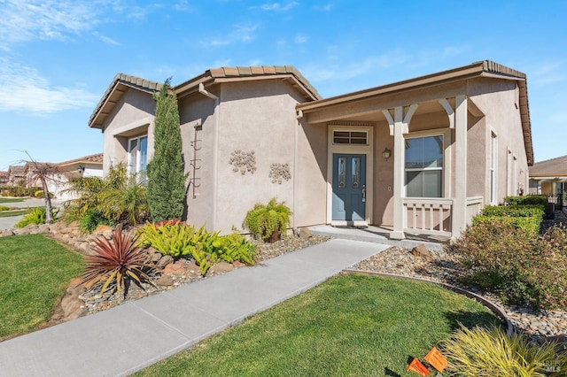 view of front of home featuring a tiled roof, a front yard, and stucco siding