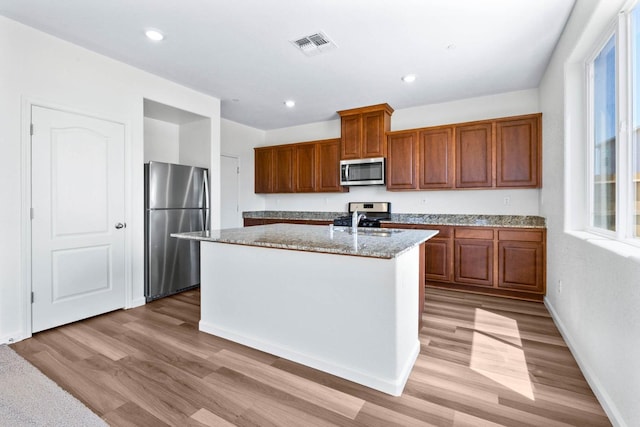 kitchen with visible vents, light wood-type flooring, brown cabinetry, and appliances with stainless steel finishes