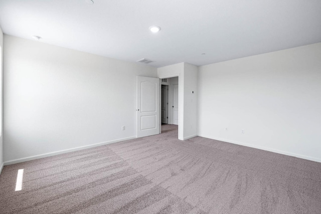 carpeted spare room with visible vents and baseboards