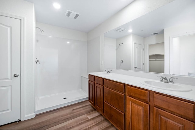 bathroom featuring a shower stall, wood finished floors, a sink, and visible vents