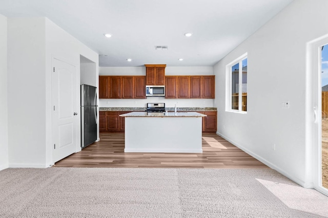 kitchen featuring visible vents, an island with sink, recessed lighting, stainless steel appliances, and light carpet