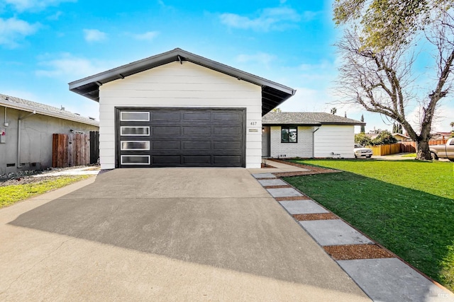 view of front of house with an attached garage, driveway, fence, and a front yard