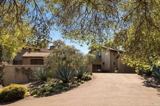 view of front of home with driveway, a tile roof, fence, and stucco siding