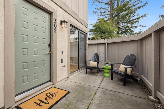 doorway to property with a patio area, fence, and stucco siding