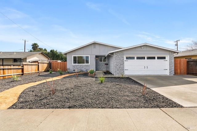 ranch-style home featuring a garage, fence, driveway, stone siding, and board and batten siding