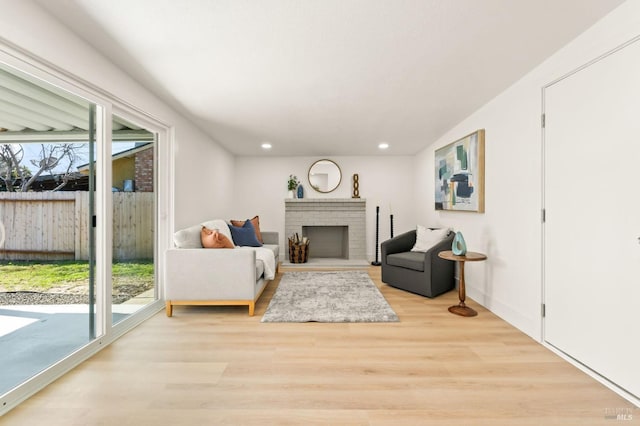 living room featuring light wood finished floors, a brick fireplace, a wealth of natural light, and recessed lighting