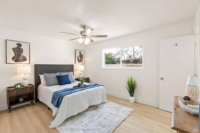 bedroom with light wood-style floors, baseboards, and a ceiling fan