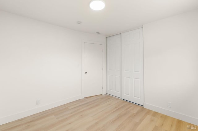 unfurnished bedroom featuring light wood-style floors, visible vents, baseboards, and a closet