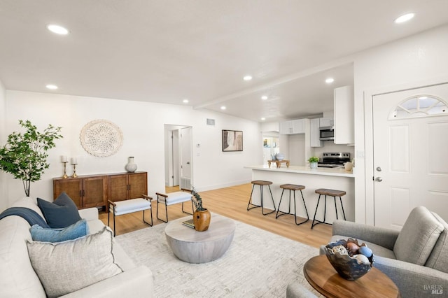 living area with vaulted ceiling with beams, recessed lighting, visible vents, light wood-style floors, and baseboards