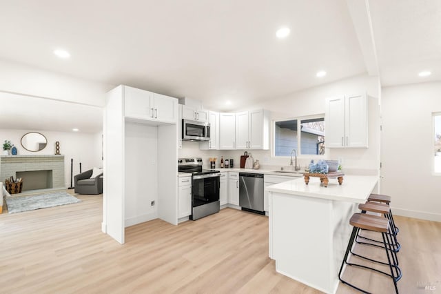 kitchen with appliances with stainless steel finishes, white cabinets, light countertops, and a kitchen bar