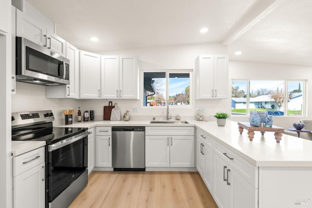 kitchen featuring stainless steel appliances, a sink, light countertops, and white cabinetry