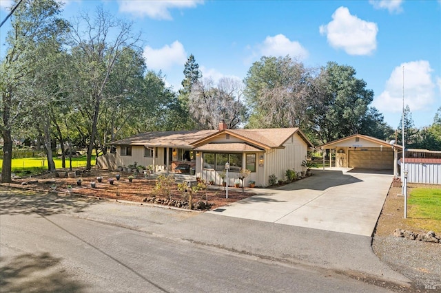 single story home featuring a porch, a detached garage, a chimney, and fence