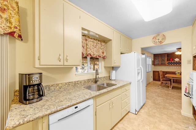 kitchen with white appliances, cream cabinetry, and a sink