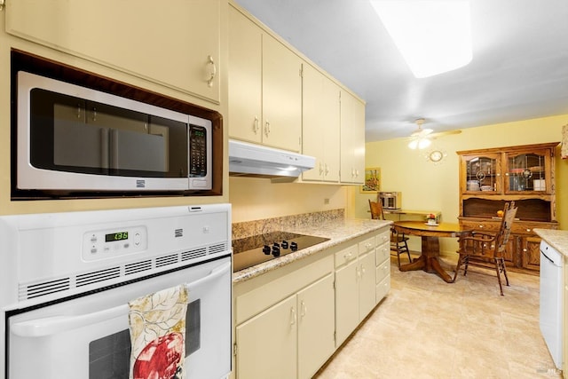 kitchen featuring stainless steel microwave, white oven, black electric cooktop, light countertops, and under cabinet range hood