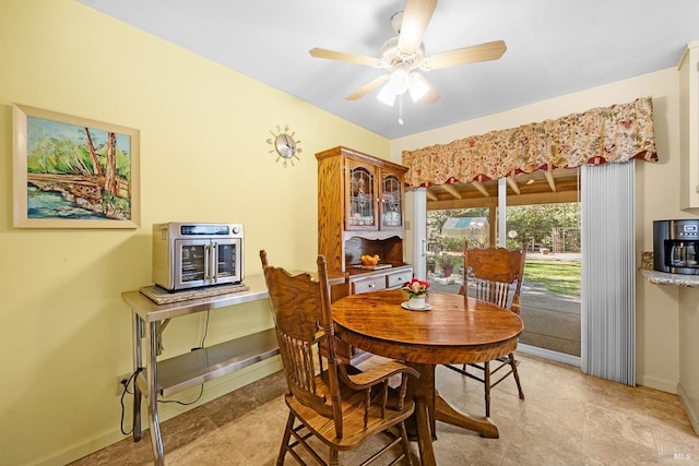 dining space with ceiling fan and baseboards