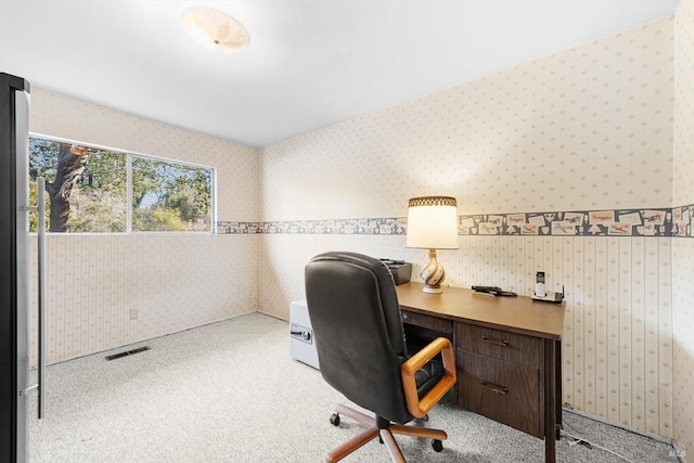 office with wallpapered walls, visible vents, and light colored carpet