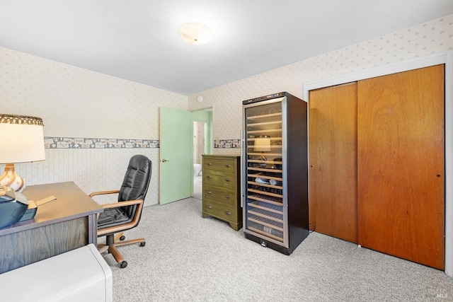 office space featuring wallpapered walls, wine cooler, and light colored carpet