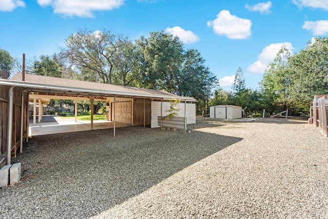 view of car parking featuring a carport, a storage unit, and driveway